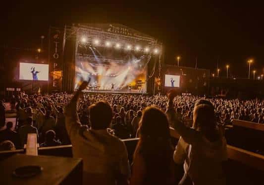 Concierto nocturno en el patio de la bodega con escenario iluminado y multitud