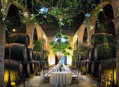 Sala de barricas decorada para una cena o evento con mesas y luces