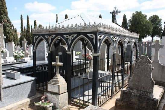 Panteón gótico con estructura metálica negra y cruces en primer plano