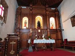 Interior de la iglesia mostrando el altar principal con retablo de madera y tres nichos con imágenes religiosas