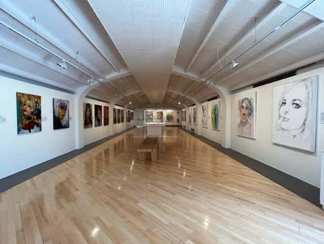 Galería interior del museo con suelo de madera y obras expuestas en las paredes