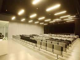 Interior del auditorio con butacas grises y escenario