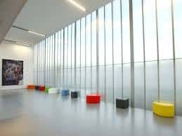 Sala de exposiciones con ventanales y mobiliario colorido
