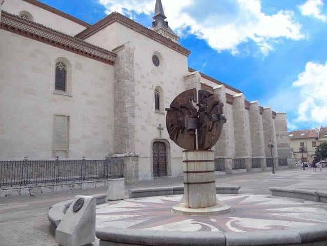 Vista de la plaza con la escultura y la iglesia al fondo
