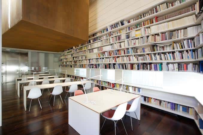 Interior de la biblioteca del centro con estanterías llenas de libros y mesas de lectura modernas