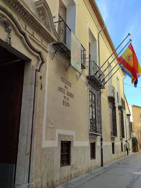 Fachada histórica del Colegio del Arte Mayor de la Seda con banderas ondeando