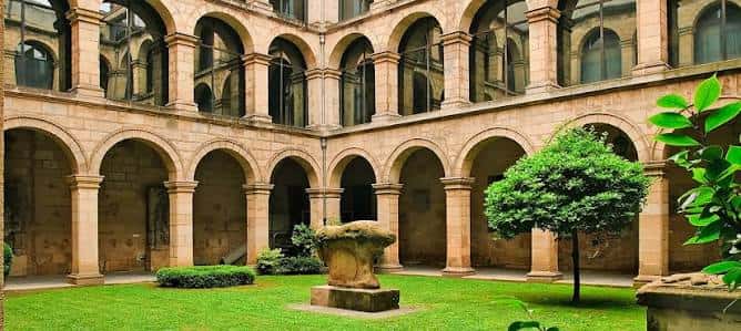 Patio interior del Euskal Museoa con arcos de piedra y jardín central