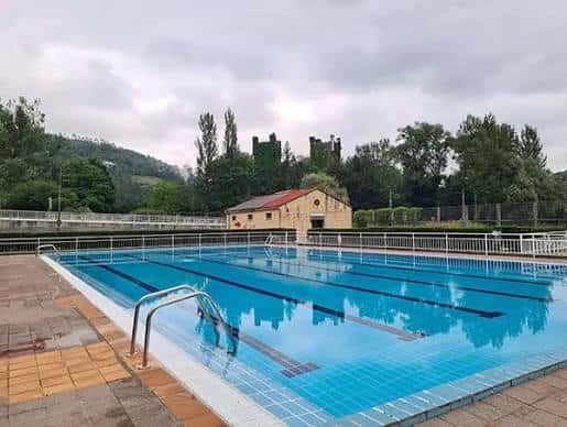 Piscina municipal de Las Caldas en un día nublado, mostrando las líneas de natación y la edificación adyacente