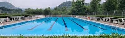 Amplia vista panorámica de la piscina al aire libre con montañas al fondo y barandillas blancas