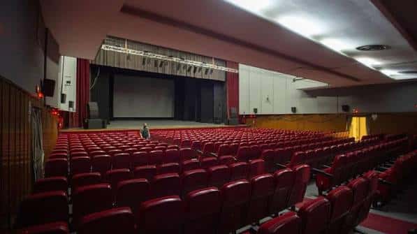 Interior del auditorio con escenario y butacas rojas dispuestas en gradas