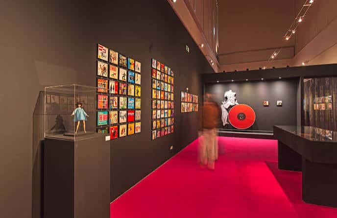 Interior de una sala de exposiciones con alfombra roja y obras de arte en las paredes