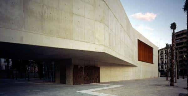 Fachada lateral del museo con grandes ventanales y palmeras al atardecer