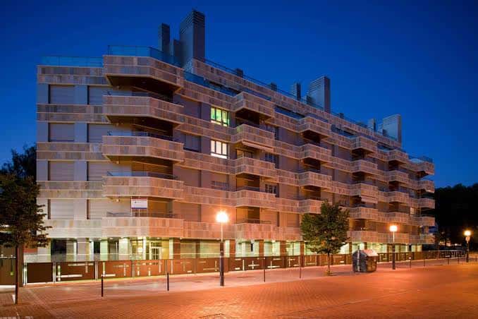 Fachada iluminada del Paseo de la Música al atardecer con luces cálidas y cielo azul oscuro