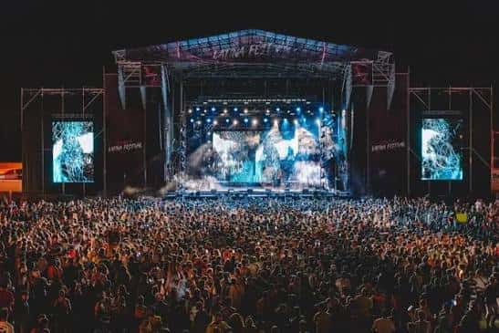 Escenario nocturno del festival con luces y pantalla gigante