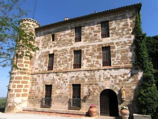 Fachada principal del Castell de Raymat con torre y muros de piedra