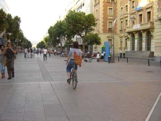 Escena cotidiana en el Bulevar Gran Capitán con ciclistas y transeúntes