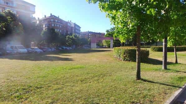 Amplia zona de césped con árboles y entrada al jardín