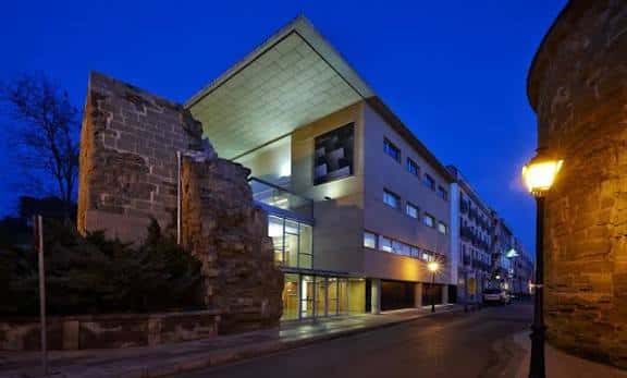 Fachada del auditorio al atardecer junto a las murallas históricas