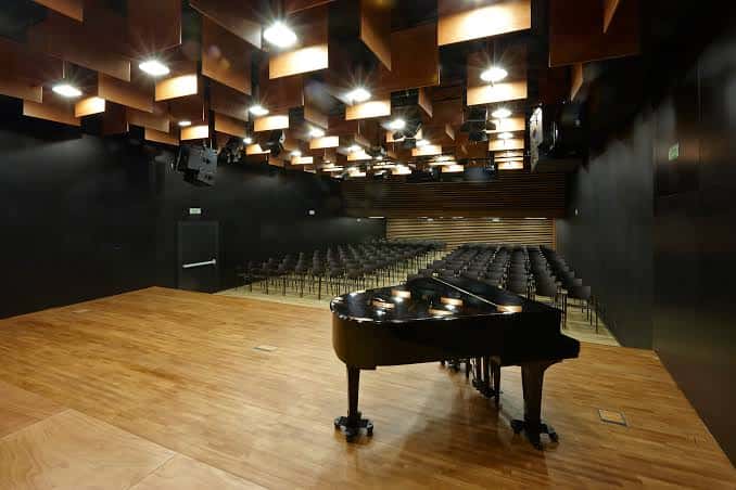 Interior del auditorio con piano de cola y butacas vacías
