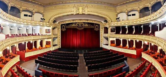Vista panorámica del interior del Teatro Cervantes con butacas rojas y balcones ornamentados