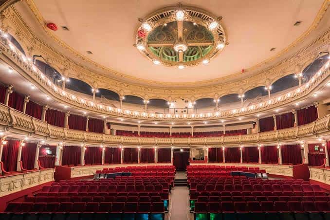 Interior del auditorio con cúpula decorada y butacas rojas bajo iluminación cálida