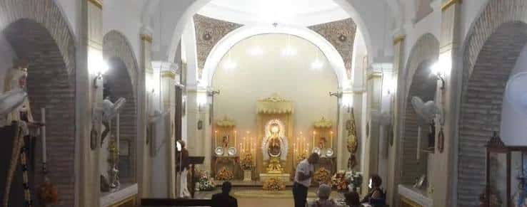 Interior de la capilla con altar principal, imágenes religiosas y decoración tradicional