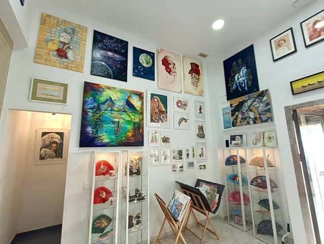 Espacio interior de la galería con arte contemporáneo, vitrinas de cerámica y obras en caballete
