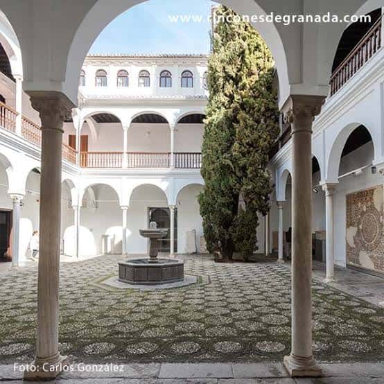 Patio interior con arcos, columnas y fuente central bajo cielo despejado