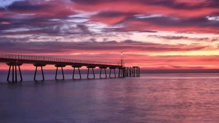 Amanecer espectacular sobre el Pont del Petroli con nubes de colores intensos