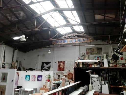 Vista general del interior del club con techo de nave industrial y obras de arte
