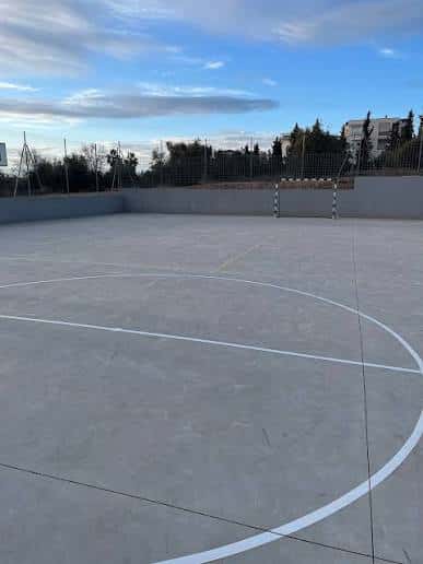 Cancha de baloncesto al aire libre del polideportivo con líneas blancas y cielo despejado
