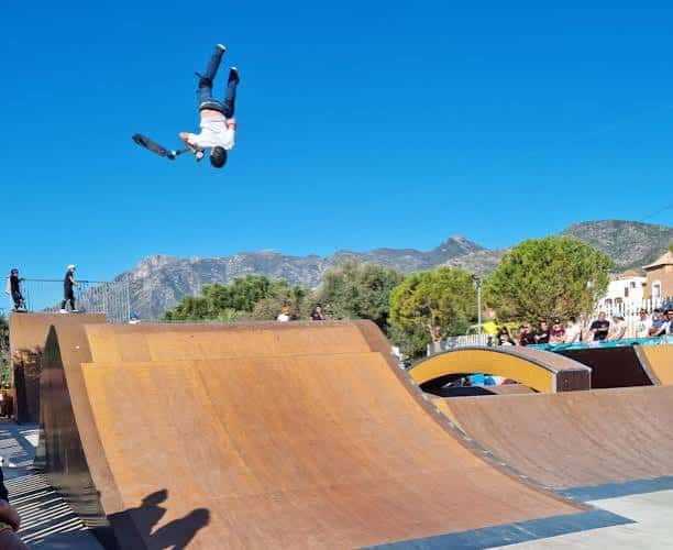 Rider realizando un truco aéreo sobre una rampa del skatepark con montañas de fondo