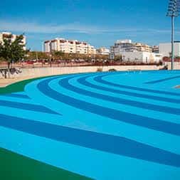 Detalle de la pista de atletismo azul con las gradas al fondo
