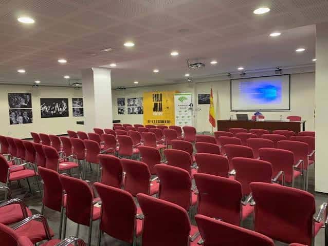 Sala de conferencias del Centro Cultural Fundación Unicaja con butacas rojas y pantalla de proyección