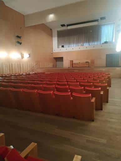 Sala de eventos con butacas rojas y escenario