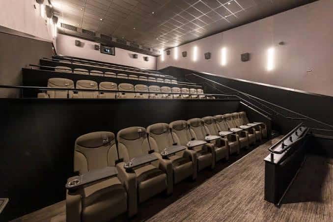 Interior de sala de cine con butacas beige y sistema de sonido envolvente
