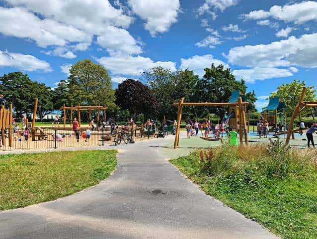 Área de juegos infantil en Central Park con estructuras de madera y césped bajo cielo azul