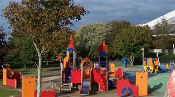 Juegos infantiles coloridos con toboganes y torres en un parque arbolado