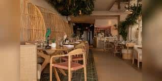 Interior del restaurante con mesas dispuestas y decoración natural con bambú y plantas