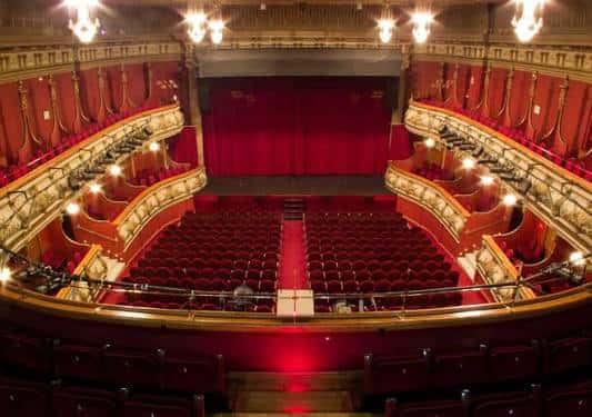 Vista panorámica del interior del Teatro Olympia con butacas rojas y balcones ornamentados