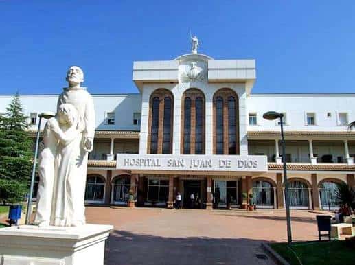 Vista frontal del Hospital San Juan de Dios en Córdoba con estatua en primer plano