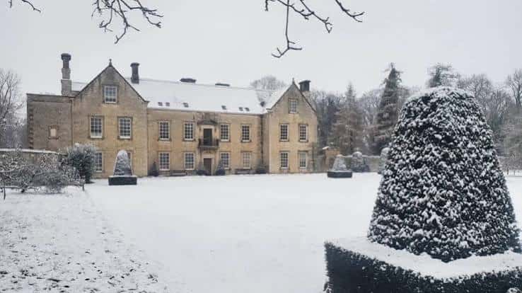 Nunnington Hall cubierto de nieve, mostrando su fachada clásica y jardines invernales