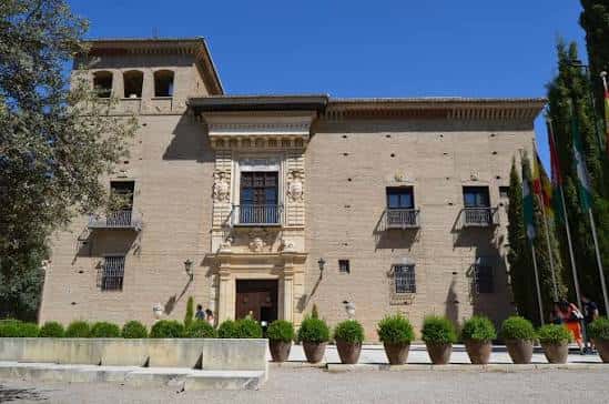 Vista frontal del Palacio de los Córdova con su fachada de ladrillo y balcones ornamentados bajo un cielo azul