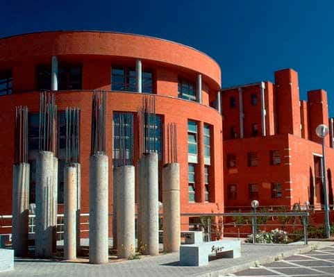 Edificio moderno de la Universidad de Alcalá con arquitectura de ladrillo rojo y columnas decorativas