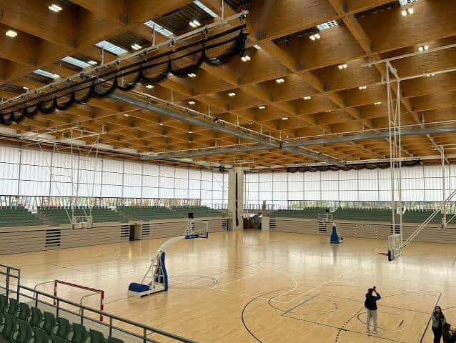 Interior del pabellón mostrando la cancha de madera y las gradas vacías