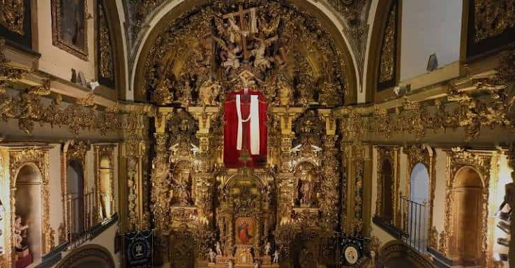 Detalle del altar mayor con el retablo barroco dorado y el crucifijo central