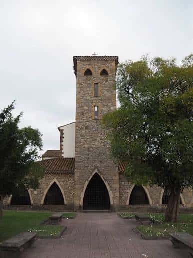 Vista exterior de la Iglesia de Santo Tomás de Granda con su torre de piedra y arcos góticos
