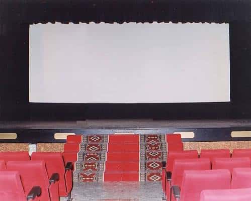 Interior del auditorio con butacas rojas y pantalla de cine