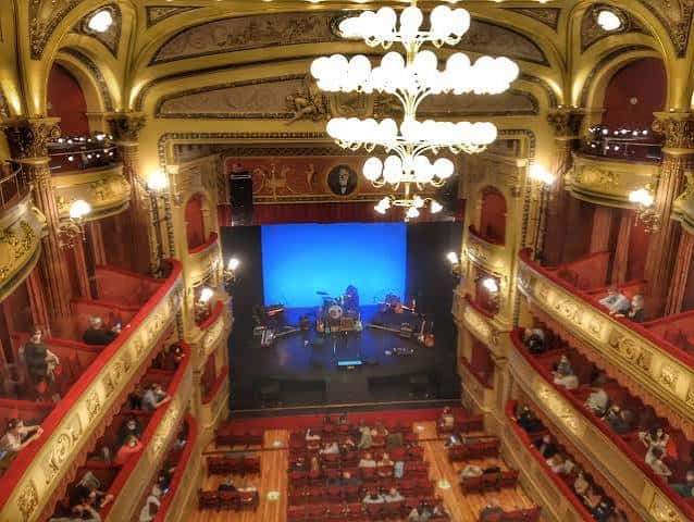 Vista panorámica del interior del auditorio con el escenario iluminado y las gradas rojas