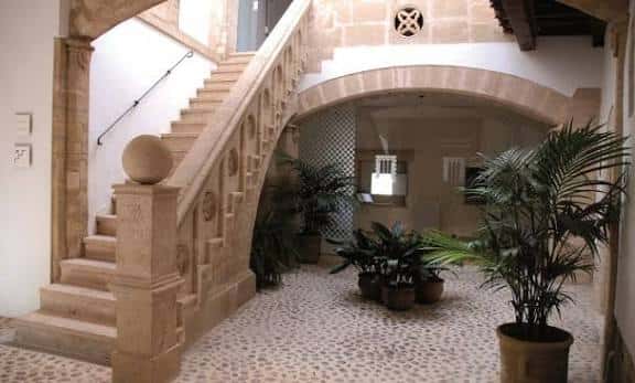 Escalera de piedra con detalles ornamentales y plantas en el patio interior del Museu Puget